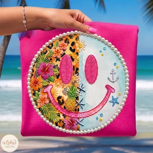 May include: A bright pink square cushion with a split smiley face design. One side has a leopard print and tropical flowers, the other a light blue background with an anchor and starfish. The design is edged with pearls.