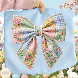May include: A large, decorative bow with a patchwork design featuring floral patterns, gingham, and polka dots in pastel colors. The bow is trimmed with white lace and faux pearls. Butterflies are embroidered on the bow. The bow is held against a light blue background.