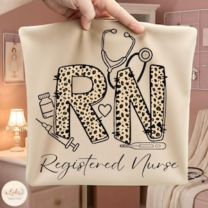 May include: A beige tote bag with the letters "RN" in a leopard print design, a stethoscope, heart, and medical icons. The words "Registered Nurse" are written in a script font below the letters.