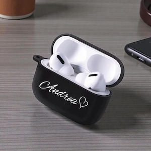 Peut inclure: Étui de protection noir pour écouteurs sans fil, ouvert pour révéler des écouteurs blancs. L'étui porte le nom "Andrea" en écriture cursive avec un symbole de cœur. Les écouteurs sont à l'intérieur d'un intérieur blanc.