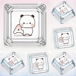 May include: A collection of six square, transparent mechanical keyboard keycaps. Each keycap features a white surface with a cartoon panda character holding a different letter of the alphabet, including A, B, C, D, E, and F in black outlines.