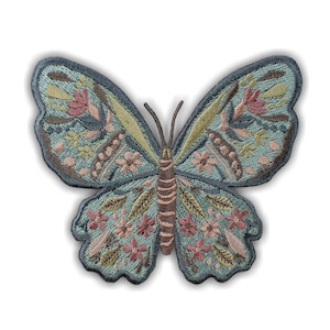 May include: Embroidered butterfly patch with a detailed design. The butterfly features a light blue background with pink, yellow, and brown floral and leaf patterns. The patch has a dark blue border and is suitable for clothing or accessories.