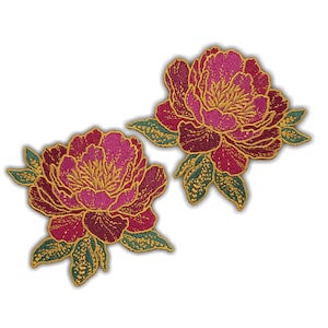 Könnte beinhalten: Zwei gestickte Aufnäher mit Pfingstrosenblüten. Die Blüten sind in leuchtendem Magenta gehalten und haben goldene Details in der Mitte und an den Rändern. Die Blätter sind grün mit goldenen Akzenten. Die Aufnäher befinden sich auf weißem Hintergrund.