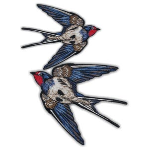 May include: Two embroidered patches of swallows in flight. The birds have blue wings, brown and white bodies, and red faces. The patches are detailed with intricate stitching, creating a realistic depiction of the birds.