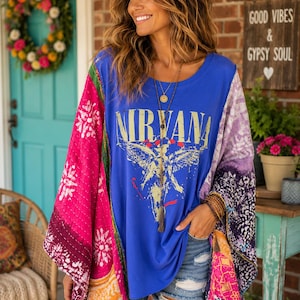 May include: A blue short-sleeved t-shirt featuring the word NIRVANA in yellow text above a graphic design, worn under a multicolored patchwork kimono with quilted stitching in shades of pink, purple, and orange, paired with distressed denim shorts.
