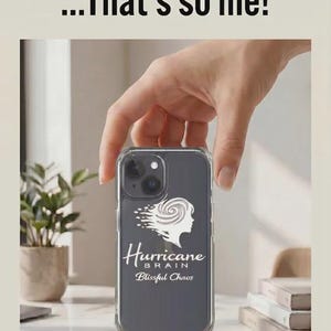 May include: Clear phone case with a gray background and the words "Hurricane Brain" and "Blissful Chaos" in white. The case also features a white graphic of a woman's silhouette with a swirling design. The text "Blissful Chaos...That's so me!" is at the top.