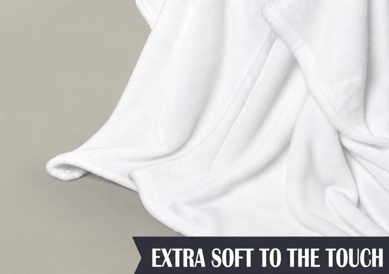 Pu&ograve; includere: Primo piano di una coperta bianca con tessuto morbido e fluido. La coperta &egrave; piegata, mostrando la trama e le cuciture lungo il bordo. Il testo in basso recita "EXTRA SOFT TO THE TOUCH."