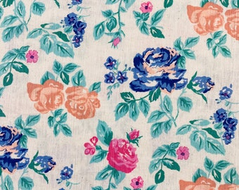 May include: Floral fabric featuring a repeating pattern of roses in shades of pink, peach, and blue, with small blue flower clusters and green leaves on a cream background. The design is reminiscent of vintage textiles.