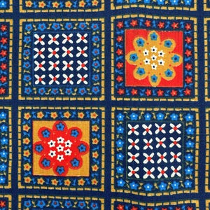 May include: Close-up of a fabric with a repeating pattern of squares. Each square contains floral or geometric designs in red, white, yellow, and blue. The background is a deep navy blue, with gold and yellow borders.