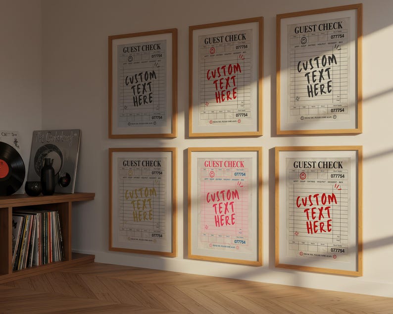 May include: Six framed prints of "Guest Check" designs with the text "Custom Text Here" in various colors. The prints are in wooden frames and are displayed on a light-colored wall. A wooden shelf with vinyl records and books is visible.