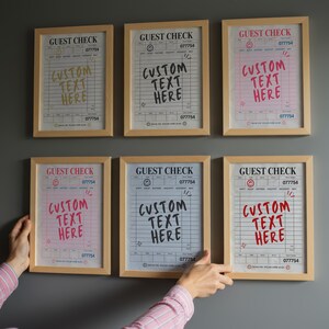 May include: Six framed guest check prints with the text "GUEST CHECK" and "CUSTOM TEXT HERE" in various colors. The prints are in wooden frames and are displayed on a gray wall. The prints have a vintage aesthetic.