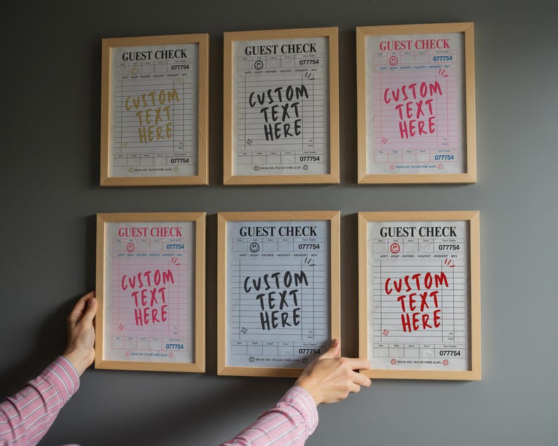 May include: Six framed guest check prints with the text "GUEST CHECK" and "CUSTOM TEXT HERE" in various colors. The prints are in wooden frames and are displayed on a gray wall. The prints have a vintage aesthetic.