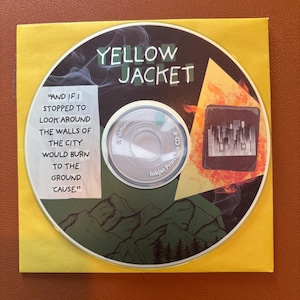 May include: A CD with the text "YELLOW JACKET" in white letters on a black background. The CD is in a yellow paper sleeve. The CD has a graphic of a city skyline engulfed in flames and a quote: "AND IF I STOPPED TO LOOK AROUND THE WALLS OF THE CITY WOULD BURN TO THE GROUND 'CAUSE."