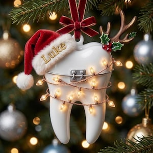 May include: A white tooth-shaped Christmas ornament featuring a red velvet Santa hat with the name Luke embroidered in gold, a metal dental bracket, a string of warm white fairy lights, and a brown reindeer antler accent with holly berries.