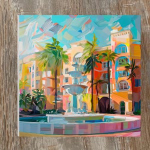 May include: An impressionistic painting of a building with a fountain and palm trees. The artwork features a multi-tiered fountain in the foreground, with a colorful building and palm trees in the background. The color palette includes shades of orange, yellow, blue, and green.