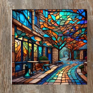 May include: A colorful stained-glass art print depicting a courtyard scene. The artwork features a mosaic of blues, oranges, and greens, with a tree canopy overhead. The scene includes tables, a pathway, and architectural details, creating a vibrant and artistic representation.