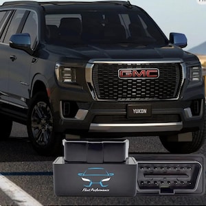 May include: A dark gray GMC Yukon SUV with a black front grill and the word "YUKON" on the license plate. In the foreground, a black box with the text "Fleet Performance" and a car logo is displayed, along with an OBD2 port.
