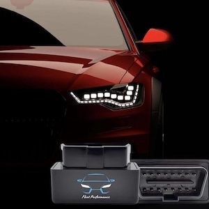 Può includere: Un'auto rosso scuro con fari bianchi brillanti sullo sfondo. In primo piano, uno scanner OBD2 nero con la scritta "Fleet Performance" e una grafica di un'auto. Lo scanner ha una forma rettangolare con una porta.