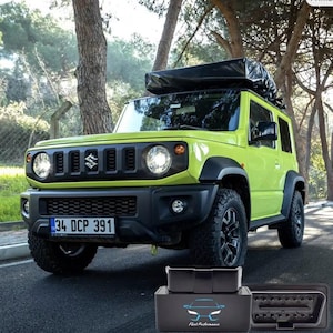 May include: A lime green Suzuki Jimny SUV with black accents and a roof rack is parked on a paved road. The vehicle has a black front grill, round headlights, and a license plate. A black OBD2 scanner with the text "Fleet Performance" is in the foreground.