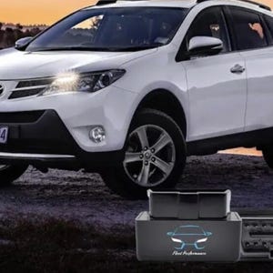 May include: White SUV with black accents, parked outdoors. The vehicle has a license plate and a roof rack. A black device with the text "Fleet Performance" is in the foreground.