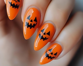 May include: Almond-shaped fingernails painted with a glossy bright orange polish. Each nail features a black graphic design of a jack-o'-lantern face, consisting of two triangular eyes and a jagged, toothy mouth centered on the nail surface.