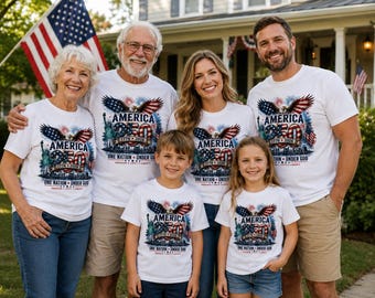 May include: A group of white t-shirts featuring a graphic print of an eagle with spread wings, the Statue of Liberty, fireworks, and the text America 250th 1776-2026 One Nation Under God Freedom Unity Liberty, worn by a family of six people.