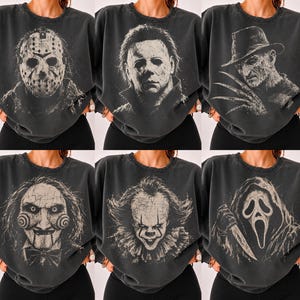 Può includere: Una collezione di sei felpe girocollo grigio antracite, ognuna caratterizzata da una stampa grafica invecchiata color bianco sporco di un classico personaggio dei film horror, tra cui Jason Voorhees, Michael Myers, Freddy Krueger, Billy, Pennywise e Ghostface.