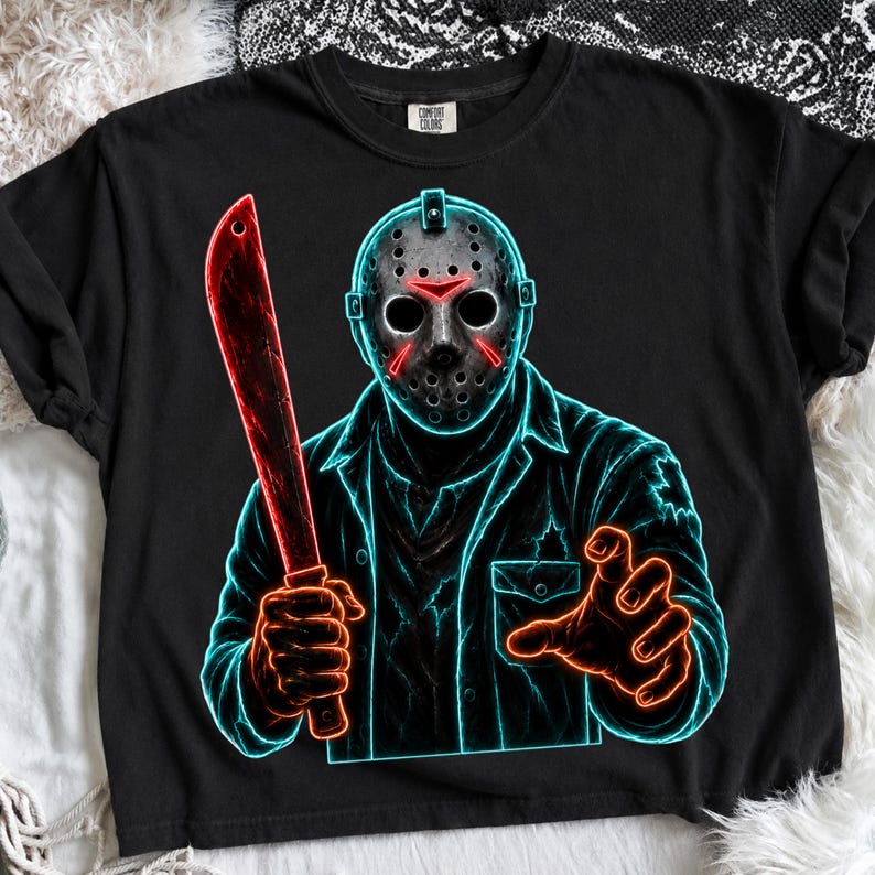 May include: A black t-shirt featuring a neon-style graphic of a hockey-masked figure holding a machete. The design uses vibrant blue outlines and red accents to depict the character, who wears a collared shirt with a chest pocket and distressed details.