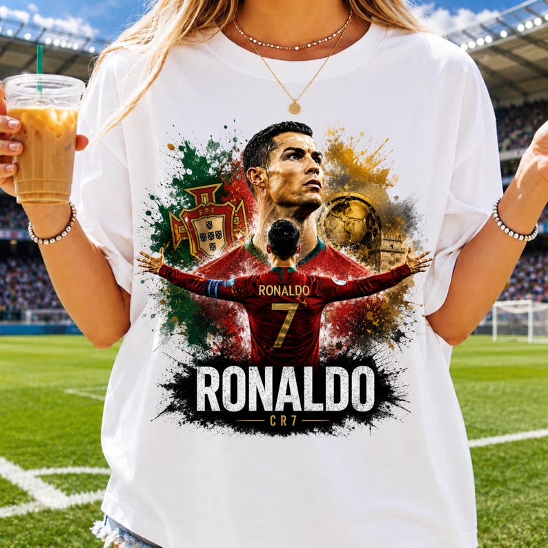 May include: A white t-shirt featuring a graphic print of soccer player Cristiano Ronaldo. The design includes a portrait, a back view of the player in a red jersey with the number 7, the Portugal national team crest, and the text RONALDO CR7.
