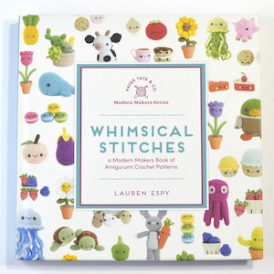 May include: A square book titled Whimsical Stitches: a Modern Makers Book of Amigurumi Crochet Patterns by Lauren Espy. The white cover features a colorful pattern of various crocheted items including animals, plants, and food with faces.