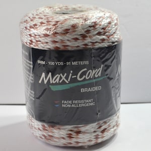 May include: A spool of white and copper-colored braided Maxi-Cord wrapped in clear plastic. The black label displays the text 6MM - 100 YDS - 91 METERS, Maxi-Cord, BRAIDED, FADE RESISTANT, and NON-ALLERGENIC in white and teal lettering.