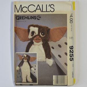 May include: A McCall's sewing pattern envelope for a Gremlins character costume, labeled 9255 size Large. The front features a brown and white plush creature with large ears and eyes, shown in a full-body view and a close-up portrait on the packaging.