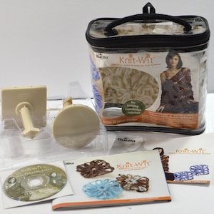May include: A Bucilla Knit-Wit loom kit featuring a clear plastic carrying case with a black handle, two beige plastic loom components, an instructional DVD, and printed project worksheets showing various yarn flower designs.