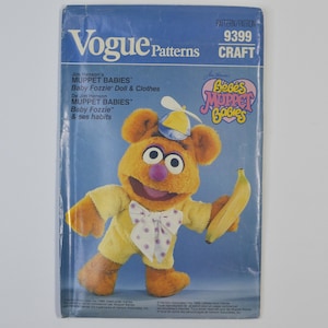 May include: A vintage Vogue Patterns craft pattern featuring Baby Fozzie from Muppet Babies. The cover shows a plush Fozzie Bear doll in a yellow outfit, holding a banana. The pattern is labeled "9399 CRAFT" and includes the text "Muppet Babies".