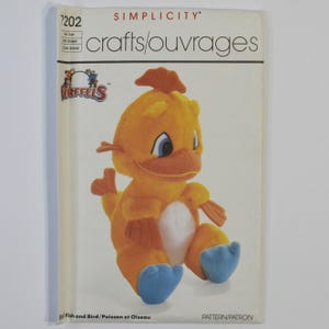 May include: A Simplicity 7202 crafts pattern envelope featuring a Fireffels graphic of a yellow plush creature with a white belly, blue feet, and orange fins. The text reads Simplicity, 7202, crafts/ouvrages, Fireffels, and Fish and Bird/Poisson et Oiseau.