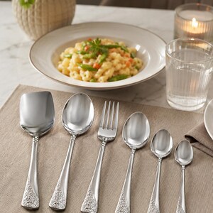 May include: A set of six stainless steel utensils featuring a polished finish and intricate embossed floral detailing on the handles. The collection includes a square-edged serving spoon, a large spoon, a dinner fork, and three smaller spoons.