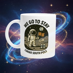 May include: White ceramic mug with a wraparound design featuring an astronaut on the moon holding a flag. The mug has the text "WE GO TO STAY" and "LUNAR SOUTH POLE". The design includes a planet Earth and two bottles labeled H2 and O2.