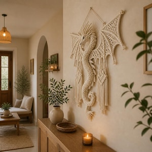 May include: A cream-colored macrame dragon wall hanging with detailed wings and a textured body. The dragon is mounted on a neutral-toned wall, adding a touch of fantasy to the room's decor. The dragon's wings span approximately 48 inches.