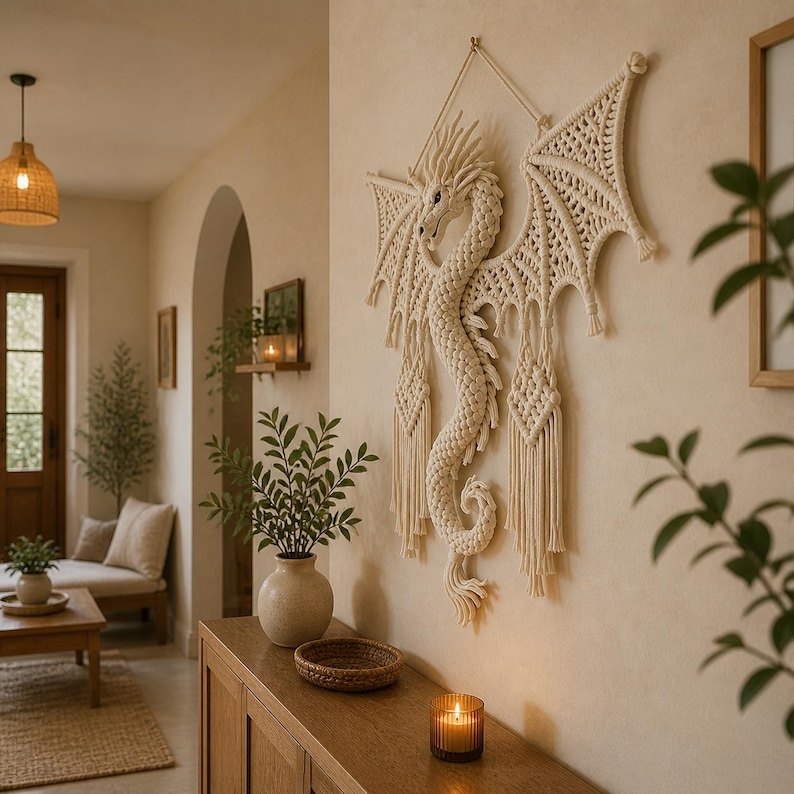 May include: A cream-colored macrame dragon wall hanging with detailed wings and a textured body. The dragon is mounted on a neutral-toned wall, adding a touch of fantasy to the room's decor. The dragon's wings span approximately 48 inches.