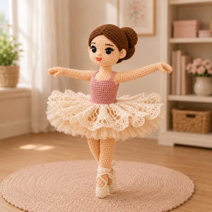 May include: A crocheted ballerina doll with brown hair in a bun, wearing a pink leotard and a cream-colored tutu. The doll is posed en pointe, with arms outstretched. The doll is approximately 12 inches tall.