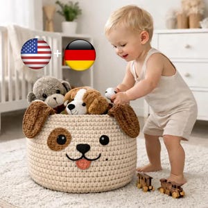 Może przedstawiać: Beżowy, szydełkowy kosz do przechowywania w kształcie psa wypełniony pluszowymi zwierzętami. Kosz ma brązowe uszy, oczy i język. Małe dziecko bawi się zabawkami i drewnianymi zabawkami-pociągami.