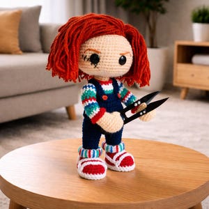 May include: Crocheted doll with red hair, black eyes, and stitched details. The doll wears blue overalls, a striped sweater, and red and white shoes. It holds black scissors, a handmade horror-themed collectible.