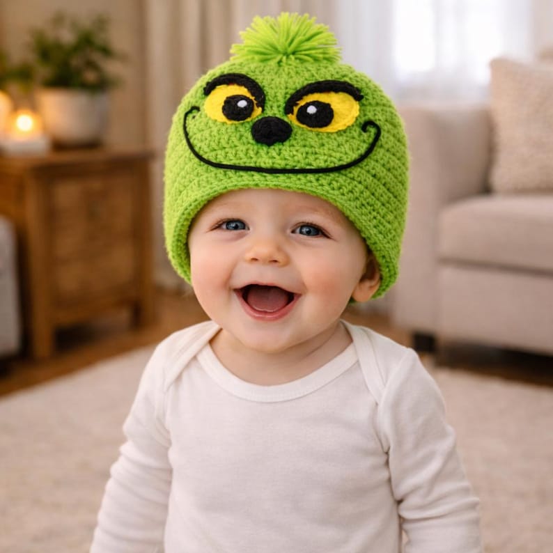 Peut inclure: Un b&eacute;b&eacute; souriant portant un bonnet vert crochet&eacute; avec un visage de Grinch. Le bonnet pr&eacute;sente des yeux jaunes, un nez noir et un sourire cousu. Le b&eacute;b&eacute; porte un body blanc &agrave; manches longues.