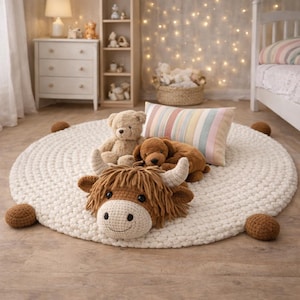 May include: A cream-colored, round, crocheted rug with a brown Highland cow pillow, a teddy bear, and a brown dog plush. A striped pillow rests on the rug. Several brown crocheted balls are placed around the rug.