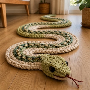 May include: A handmade, crochet snake rug in shades of green and beige. The rug is shaped like a snake, with a detailed head featuring black eyes and a red tongue. The body of the snake is a long, winding design.