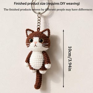 May include: A handmade crochet cat keychain, featuring brown and white yarn. The cat has a detailed face with black eyes, a pink nose, and white whiskers. The finished product size is 3.94 inches (10cm).