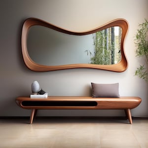 May include: A large, horizontal wall mirror with a smooth, organic, wavy wooden frame in a warm brown tone. Below it sits a long, low wooden bench with rounded edges, a single open storage shelf, and a solid rectangular gray cushion on top.