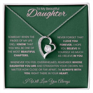 Op de afbeelding: Een zilveren ketting met een hartvormige hanger, bezet met kleine heldere stenen en een centrale, grotere heldere steen. De ketting wordt gepresenteerd in een geschenkdoos met een groene achtergrond en de tekst "To My Beautiful Daughter."