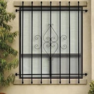 May include: Black wrought iron window security bars with a decorative central design. The bars are mounted on a light-colored stone frame, providing both security and aesthetic appeal. The window is covered with a white blind.