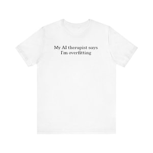 May include: White t-shirt with the text "My AI therapist says I'm overfitting" in black. The shirt is a short-sleeved crew neck style.